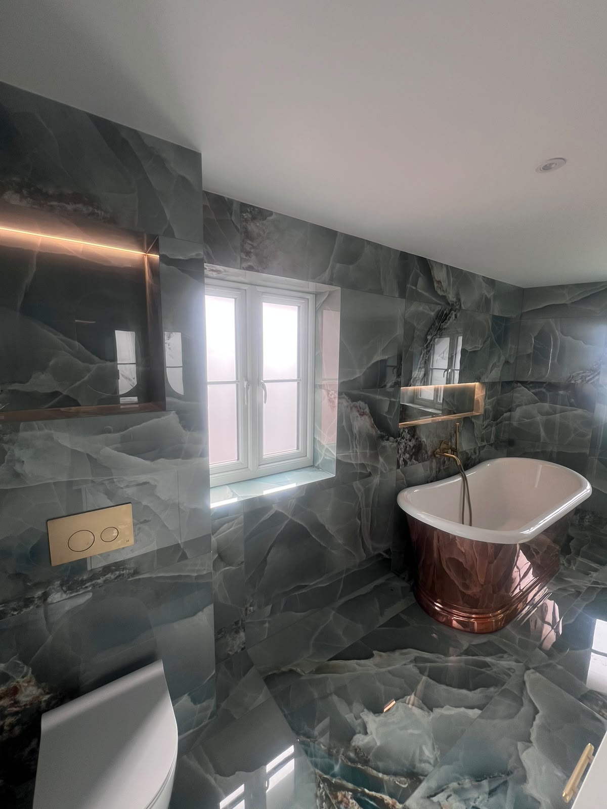 Natural stone tiled bathroom in Kent with copper freestanding bath