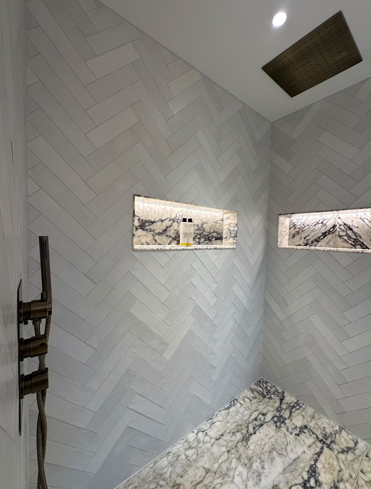 Herringbone tiling with illuminated niches in a Kent shower