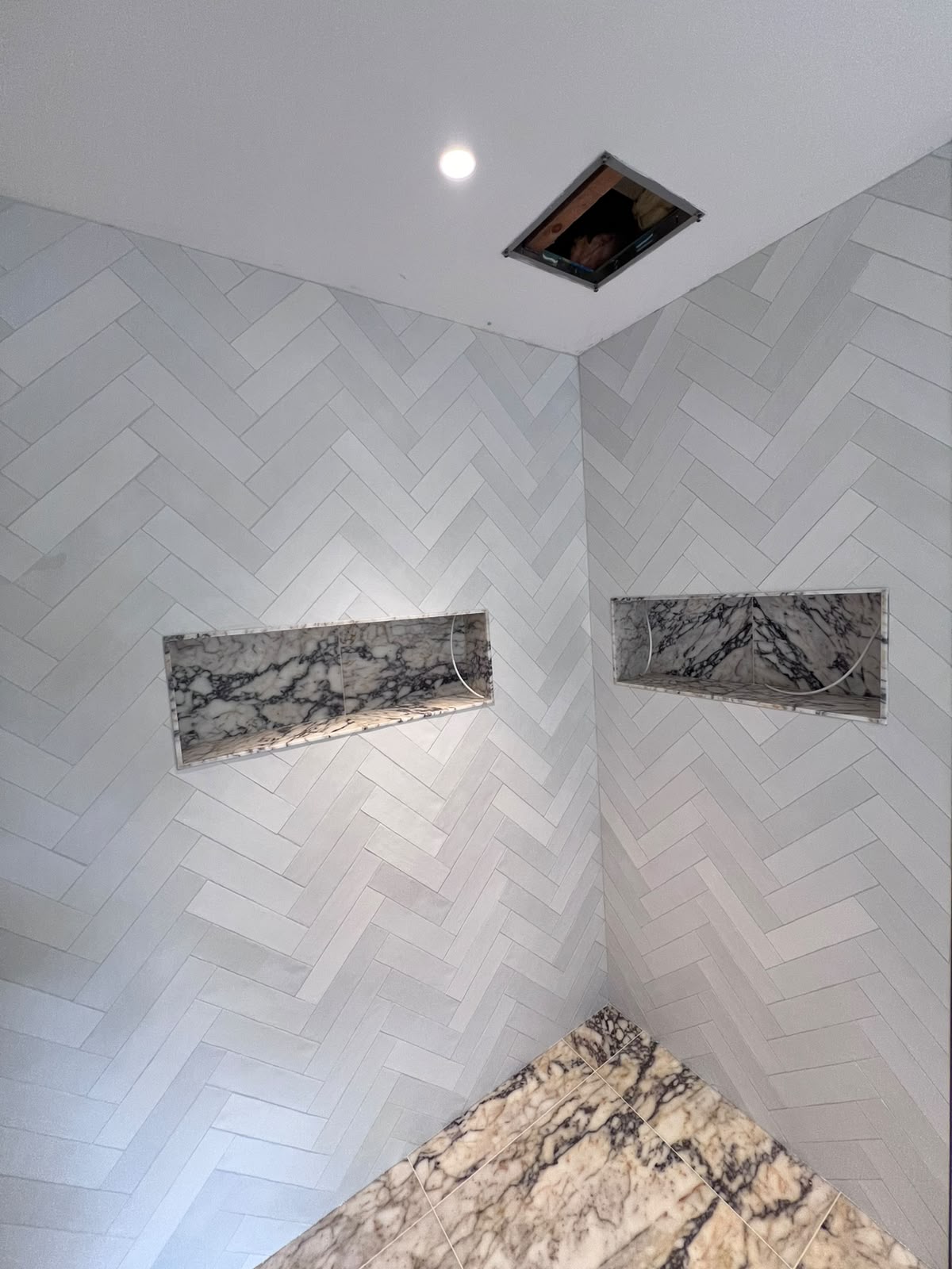 Herringbone tiled shower walls with marble niches in Kent