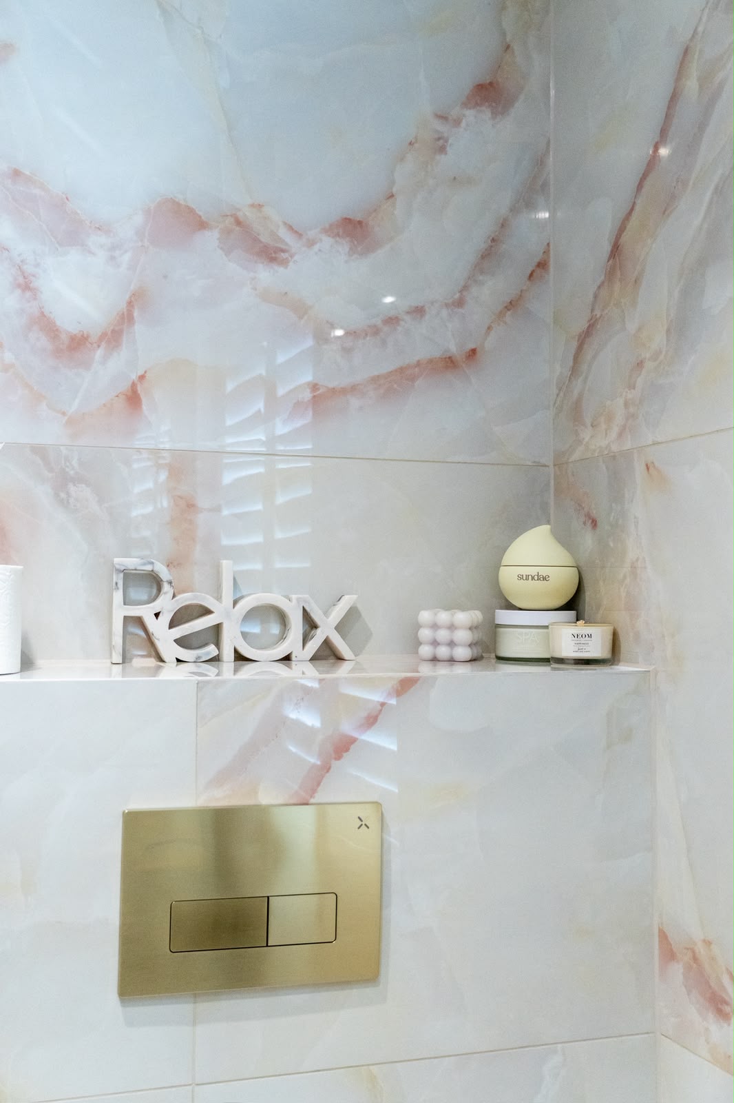Onyx-effect tiling to a Kent cloakroom with a mitred shelf and brushed brass flush plate