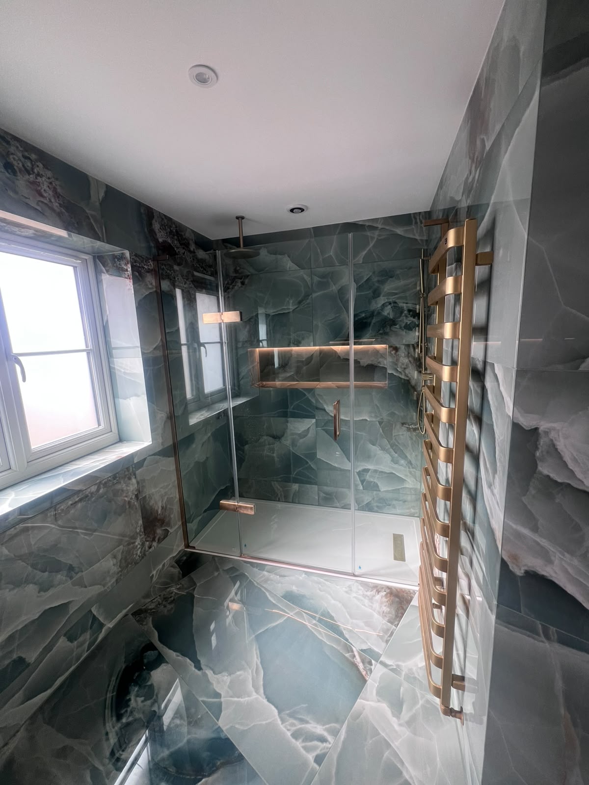 Blue onyx-effect shower with mitred edge tiling and illuminated recessed shelf in Kent