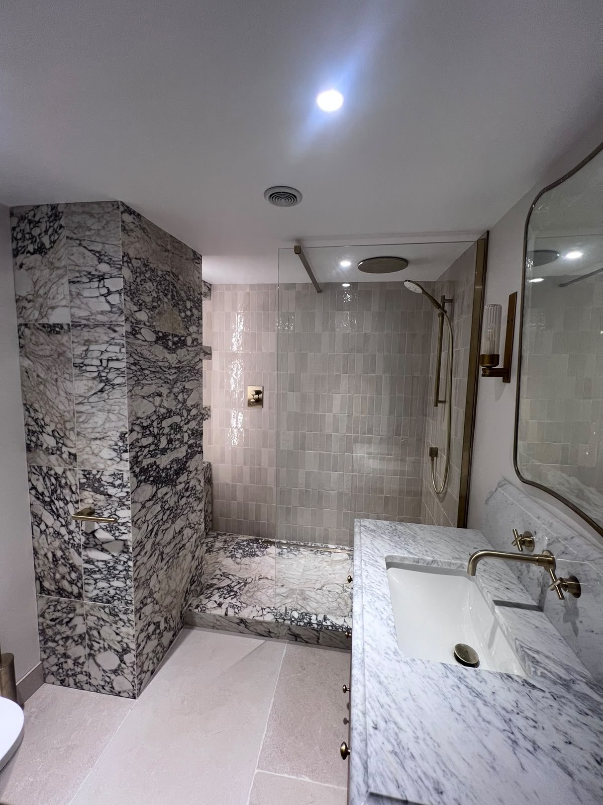 Book-matched marble slab tiling to a Kent shower wall