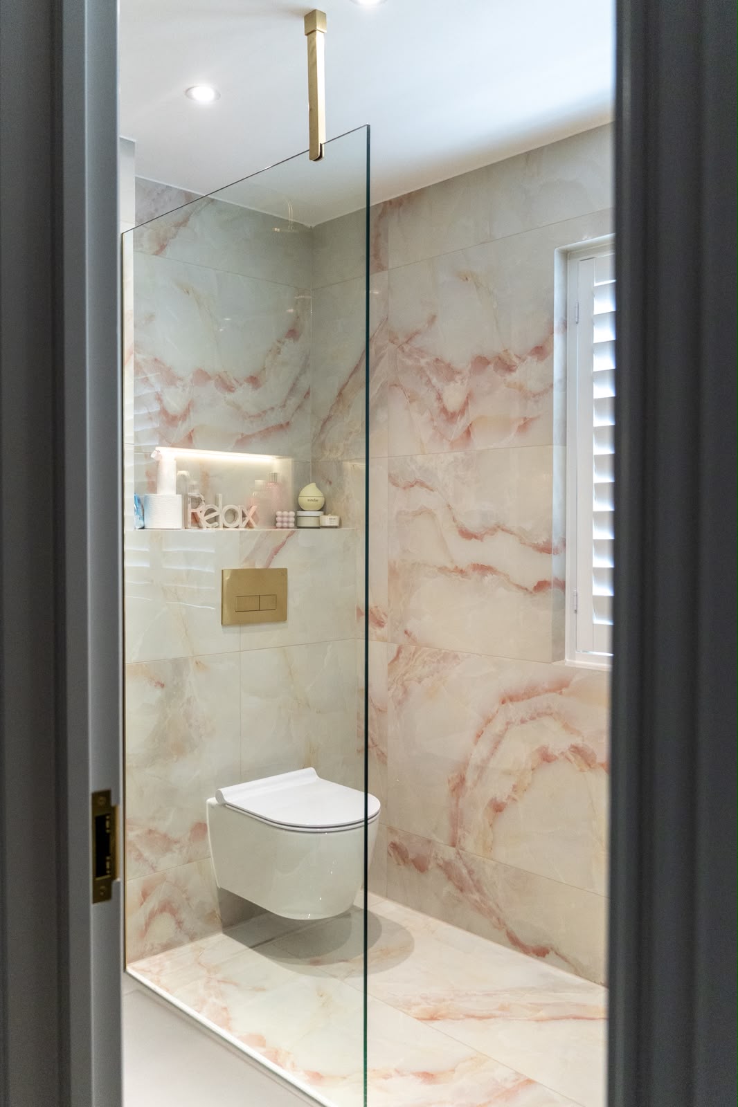 Pink onyx-effect porcelain cloakroom tiling with brass fittings in Kent