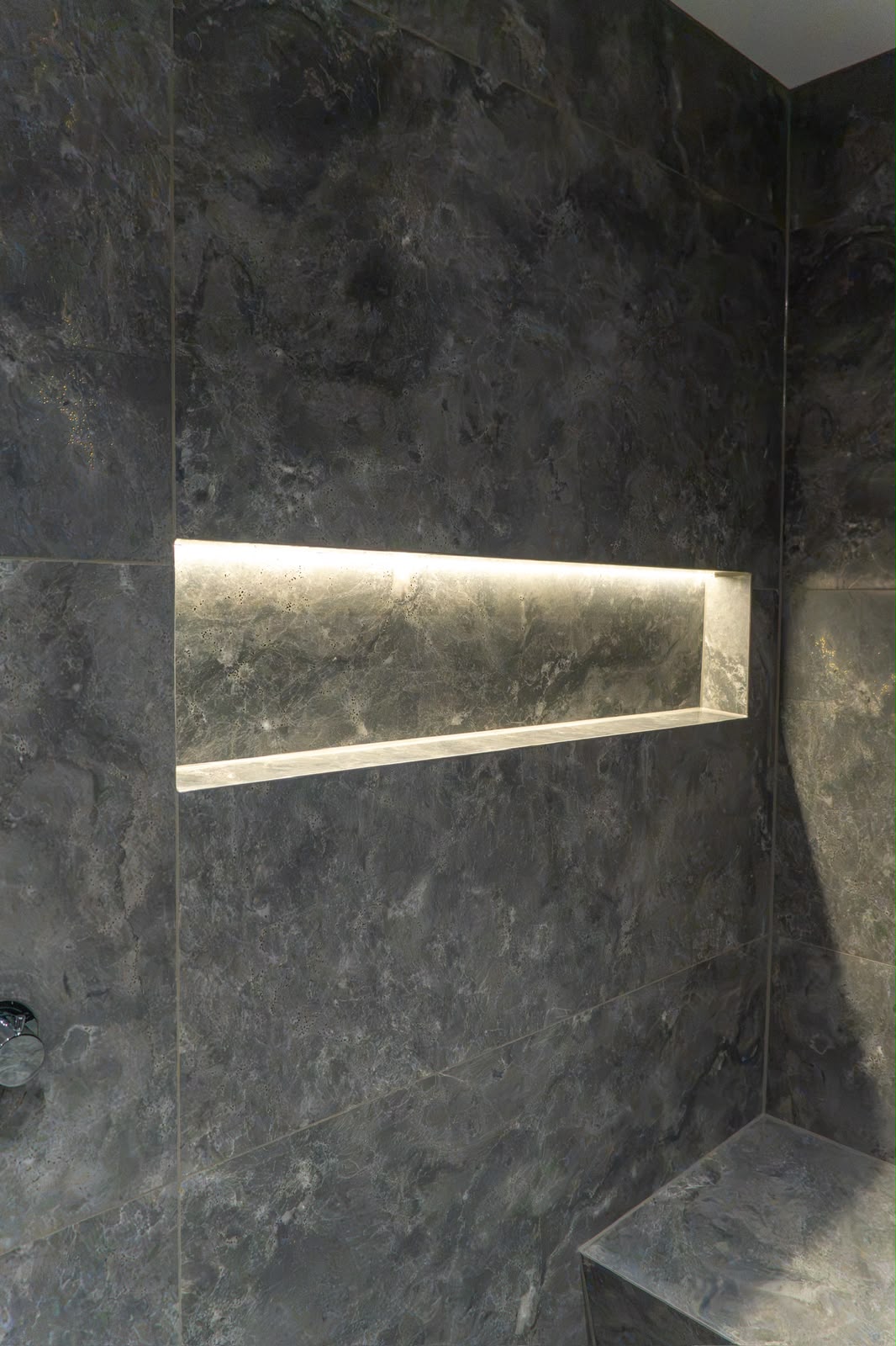 Dark marble-effect shower tiling with an illuminated recessed niche